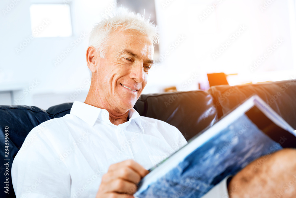 Handsome sennior man reading a book relaxing on a sofa Handsome sennior man reading a book relaxing on a sofa