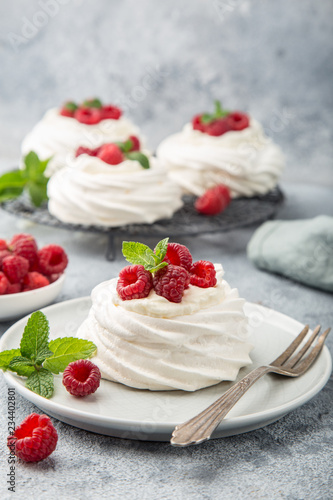 mini pavlova meringue cakes with whipped cream and fresh raspberry
