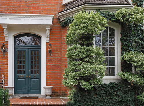 front door of brick townhouse with window surrounded by vines