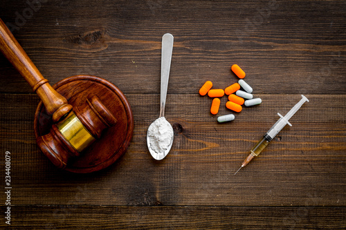 Drugs addiction, arrest for drugs. Pills, spoon with powder, syringe on dark wooden background top view