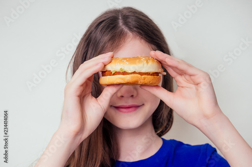 beautiful teenager girl is eating baked vegetarian burger with vegetables. Child vegan idea healthy eating concept.clear skin perfect teen acne refusal from junk food