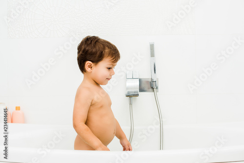 Small and cute toddler boy standing in white bathroom