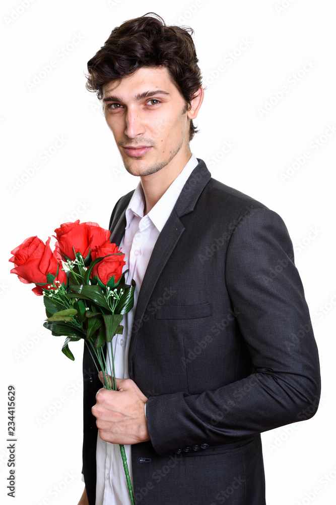Studio shot of young handsome businessman holding red roses Studio shot of young handsome businessman holding red roses