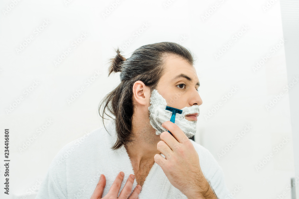 Handsome man in bathrobe shaving in bathroom Handsome man in bathrobe shaving in bathroom