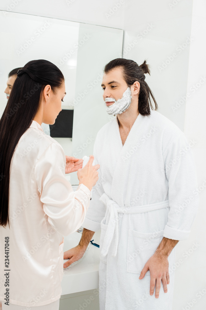 Obraz premium Woman applying shaving foam on husband face
