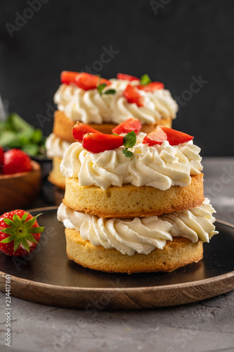 Victoria sponge cake with strawberries, jam and whipped cream on dark background. Copy space.