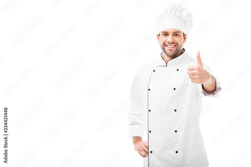 happy young chef showing thumb up and looking at camera isolated on white