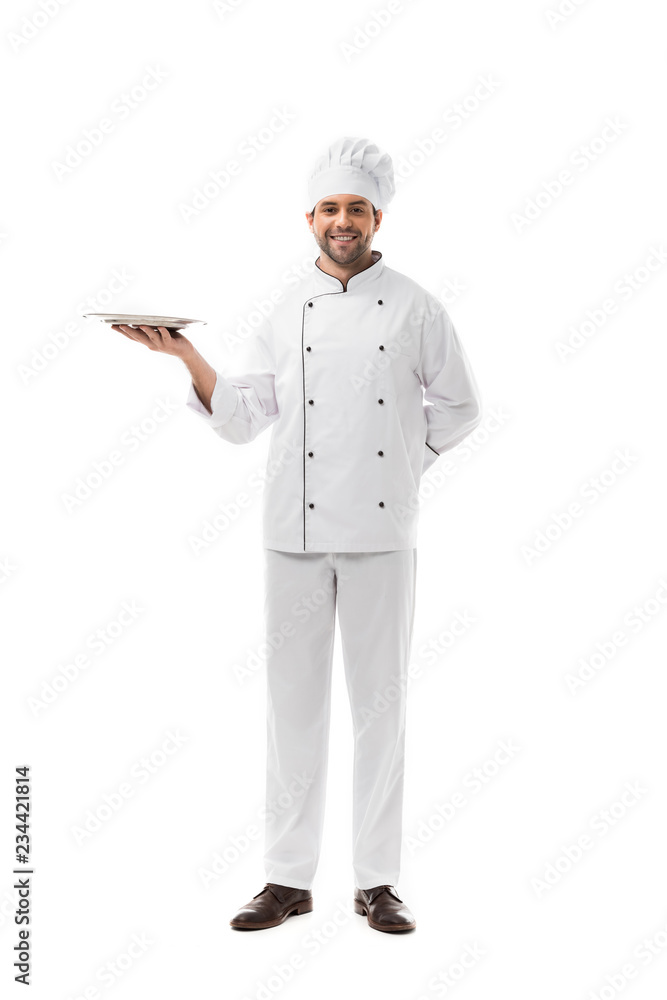 happy young chef holding empty plate and looking at camera isolated on white happy young chef holding empty plate and looking at camera isolated on white