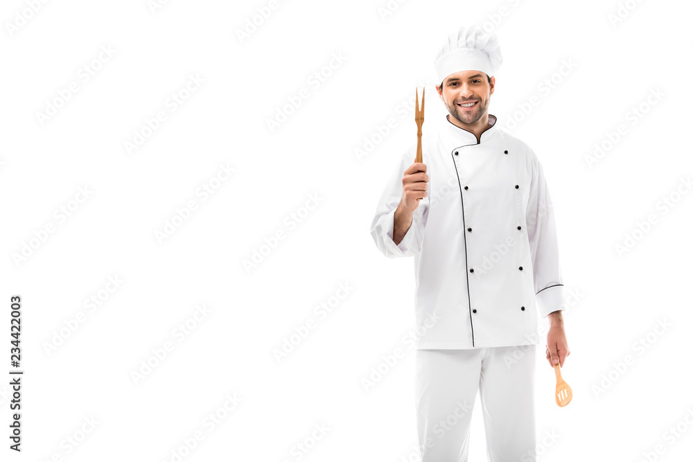 happy young chef holding kitchen utensils and looking at camera isolated on white happy young chef holding kitchen utensils and looking at camera isolated on white