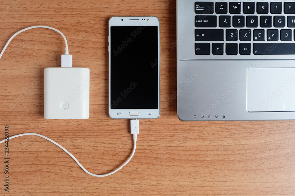Plug in USB charger from powerbank input mobile phone or cell phone and laptop computer on wooden floor,Top Plug in USB charger from powerbank input mobile phone or cell phone and laptop computer on wooden floor,Top