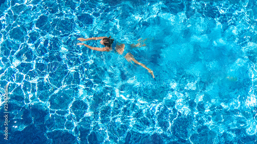 Active girl in swimming pool aerial drone view from above, young woman swims in blue water, tropical vacation, holiday on resort concept

