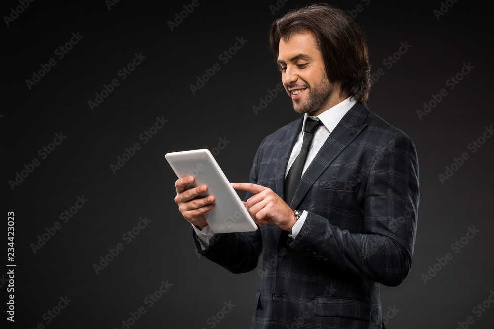 professional smiling young businessman using digital tablet isolated on black professional smiling young businessman using digital tablet isolated on black