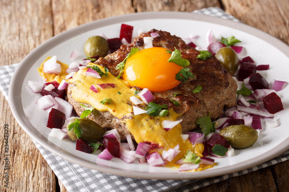 Traditional Danish steak Pariserbof with egg yolk and mustard, served with onions, capers and beet close up. horizontal Traditional Danish steak Pariserbof with egg yolk and mustard, served with onions, capers and beet close up. horizontal