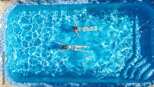 Active girls in swimming pool water aerial drone view from above  children swim  kids have fun on tropical family vacation  holiday resort concept  