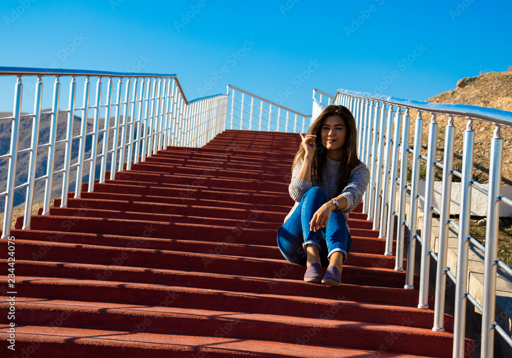 a young woman got an idea on the red stairs in the mountains