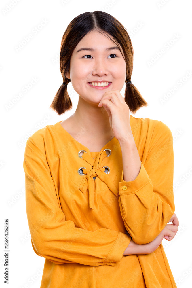 Studio shot of young happy Asian woman smiling while thinking Studio shot of young happy Asian woman smiling while thinking