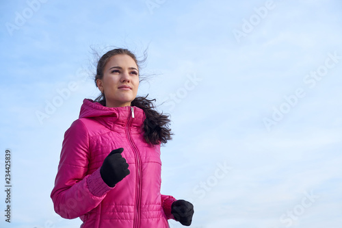 Running athlete woman sprinting during winter training outside in cold snow weather. Close up showing speed and movement. photo