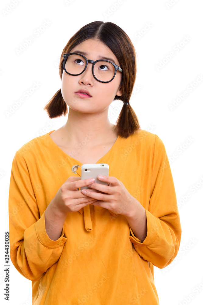 Young thoughtful Asian woman holding mobile phone Young thoughtful Asian woman holding mobile phone