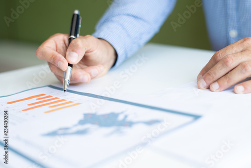 Closeup of business man analyzing bar chart. Person working at desk. Analytics concept. Cropped view.