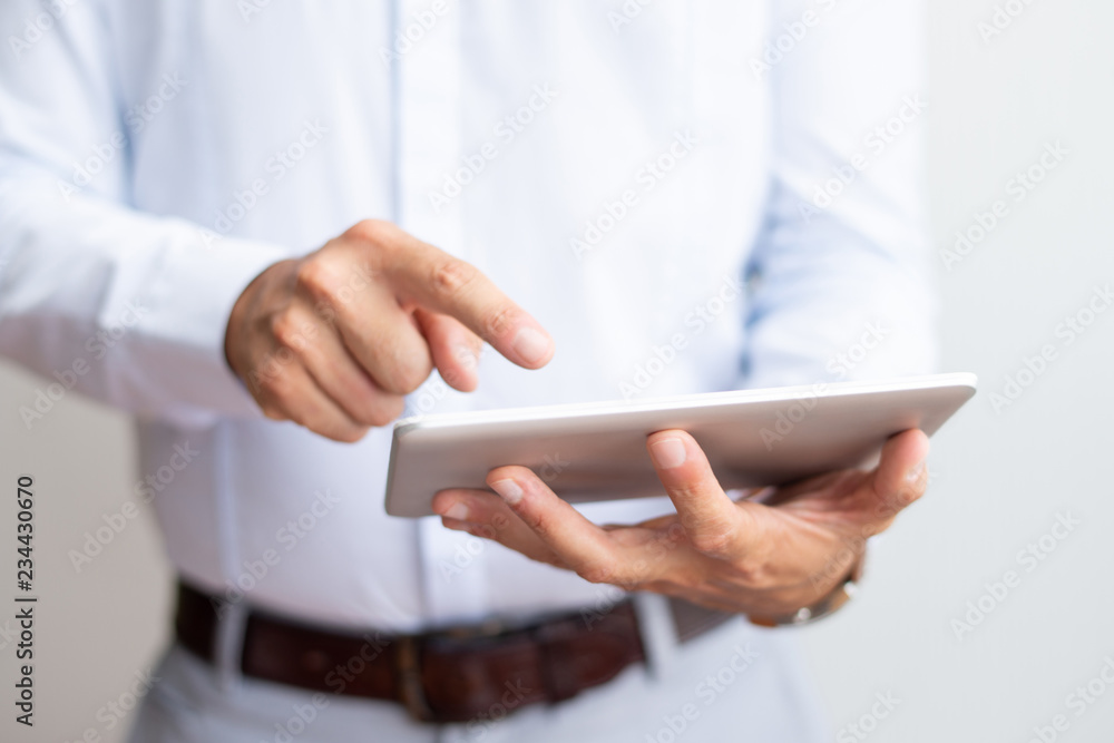 Closeup of businessman using tablet computer. Man browsing on digital device. Technology and communication concept. Cropped front view. Closeup of businessman using tablet computer. Man browsing on digital device. Technology and communication concept. Cropped front view.