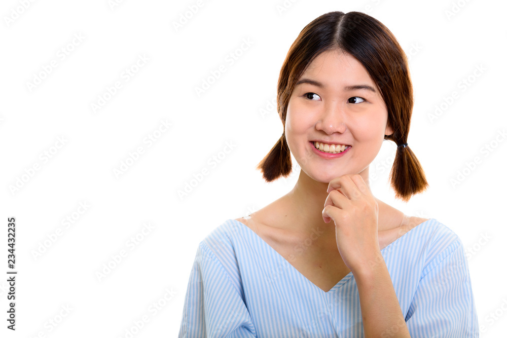 Studio shot of young happy Asian woman smiling while thinking Studio shot of young happy Asian woman smiling while thinking