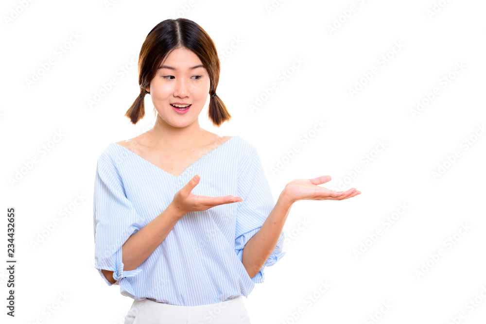 Studio shot of young happy Asian woman smiling while showing som Studio shot of young happy Asian woman smiling while showing som