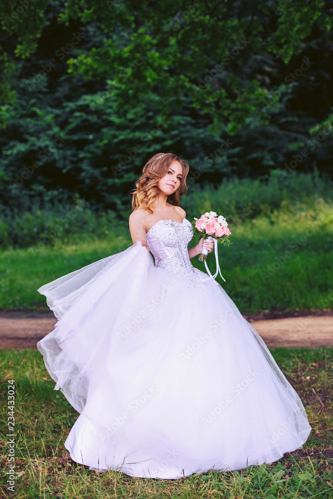 Cute bride with a bouquet of flowers walking in the nature