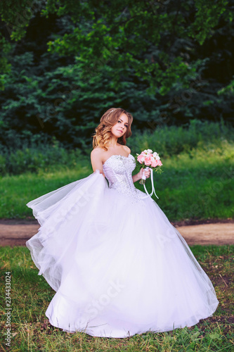 Cute bride with a bouquet of flowers walking in the nature