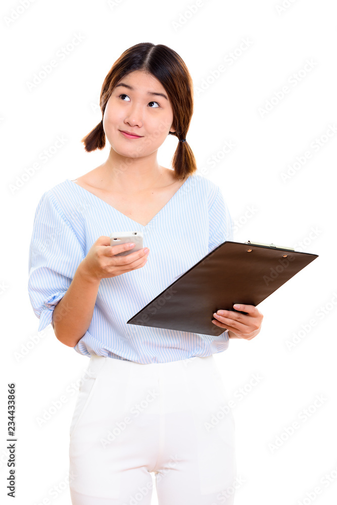 Studio shot of young thoughtful Asian woman holding mobile phone Studio shot of young thoughtful Asian woman holding mobile phone