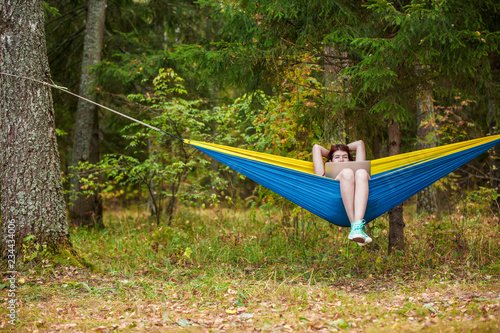Image of young woman resting in hammock with laptop in forest