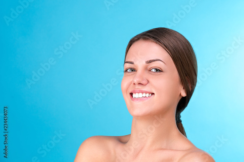 Beauty portrait of a young attractive half naked woman with perfect skin laughing and looking at camera isolated over blue background. Youth and Skin Care Concept.