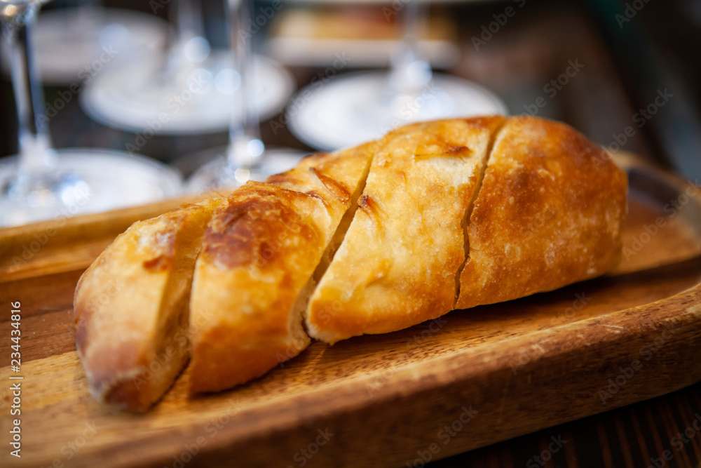 Freshly baked Italian Ciabatta bread from oven on a wooden tray for appetizer or meal starter. Looks tasty and delicious. Good source of carbohydrate. Not gluten-free. Natural light. Selective Focus. Freshly baked Italian Ciabatta bread from oven on a wooden tray for appetizer or meal starter. Looks tasty and delicious. Good source of carbohydrate. Not gluten-free. Natural light. Selective Focus.