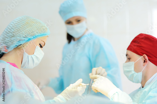 a team or group of surgeons operate on a patient in a modern operating room on the background of surgical instruments and equipment