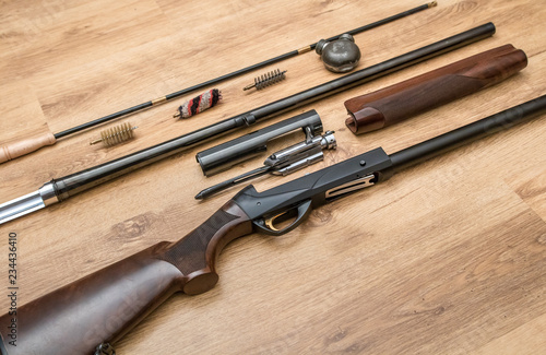 disassembled shotgun parts and cleaning kit on the wooden background photo