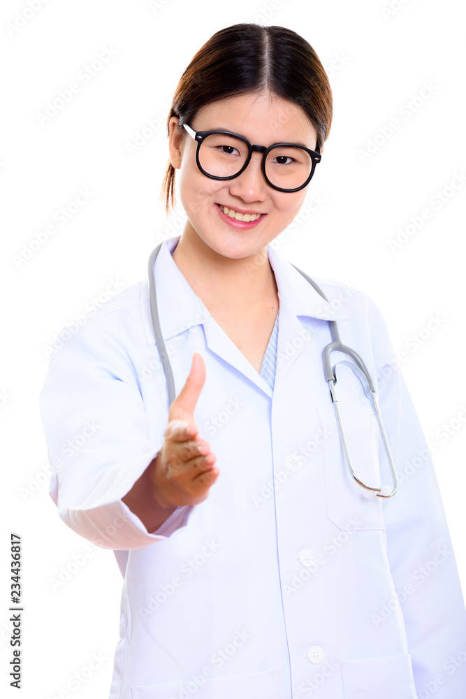 Studio shot of young happy Asian woman doctor smiling while givi Studio shot of young happy Asian woman doctor smiling while givi