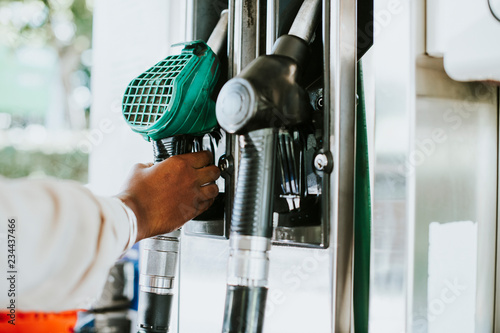 Konstfotografi Man grabbing a fuel nozzle to refuel his vehicle