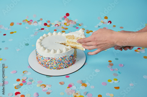 Partial view of woman taking piece of delicious cake on blue background photo