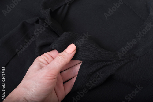 Details of black blouse in female hand. Close up. Fashion concept