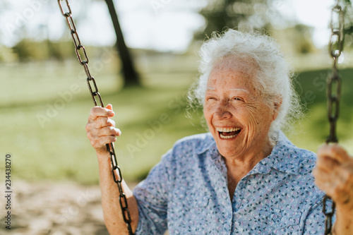 Obraz na plátně Cheerful senior woman on a swing at a playground