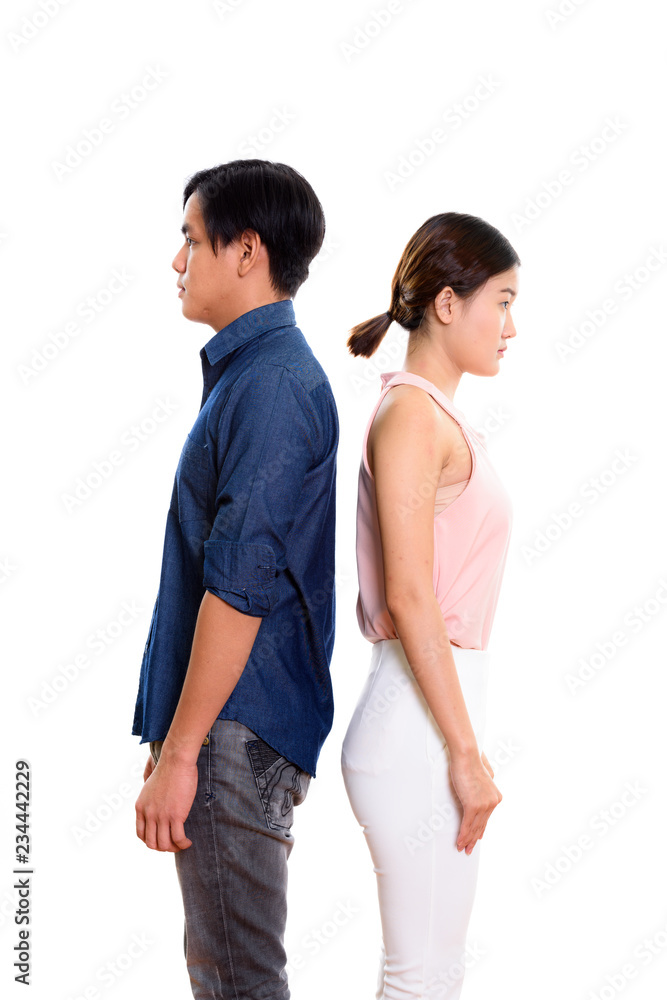 Profile view of young Asian couple with backs against each other Profile view of young Asian couple with backs against each other