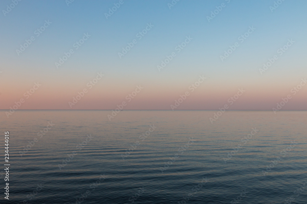 Sunset on the calm sea with smooth gradient and pastel blue and pink colors of the sky background. Beautiful nature landscape