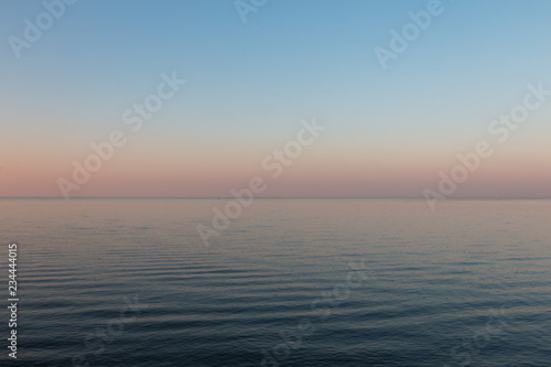Sunset on the calm sea with smooth gradient and pastel blue and pink colors of the sky background. Beautiful nature landscape
