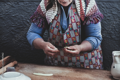 hands kneading fresh homemade orecchiette on traditional wooden table photo