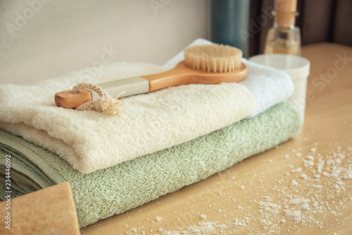 Clean soft towels with bath brush on wooden table