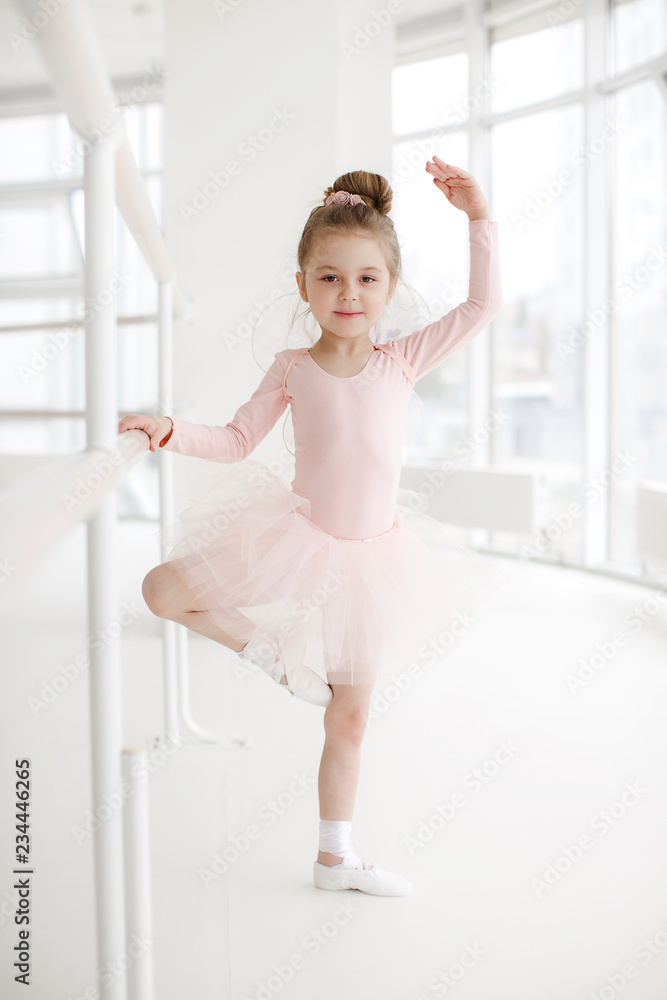 Little ballerina girl in a pink tutu. Adorable child dancing classical ballet in a white studio. Children dance. Kids performing. Young gifted dancer in a class. Preschool kid taking art lessons
