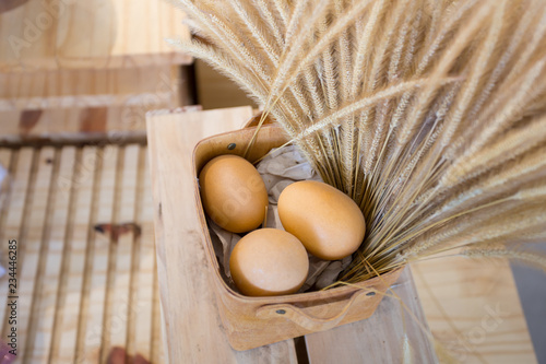 Eggs and dry poaceae in wooden basket photo