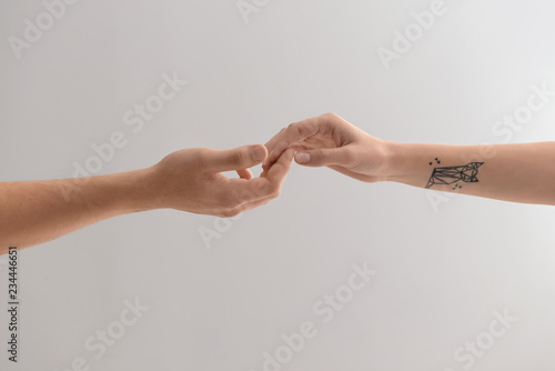 Man and woman touching fingers on light background