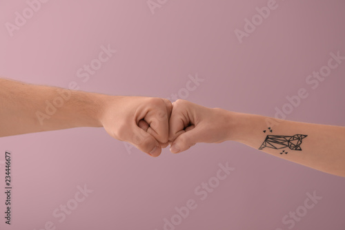 Man and woman making fist bump gesture on color background