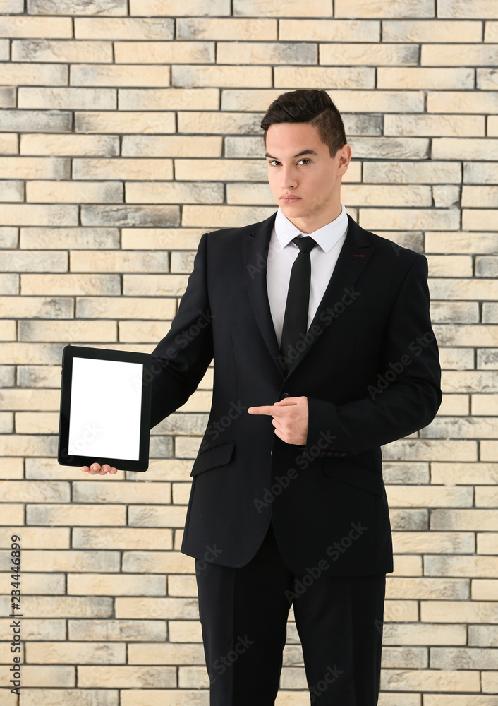 Young businessman with tablet computer against brick wall Young businessman with tablet computer against brick wall