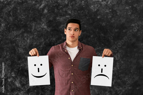Young man holding sheets of...